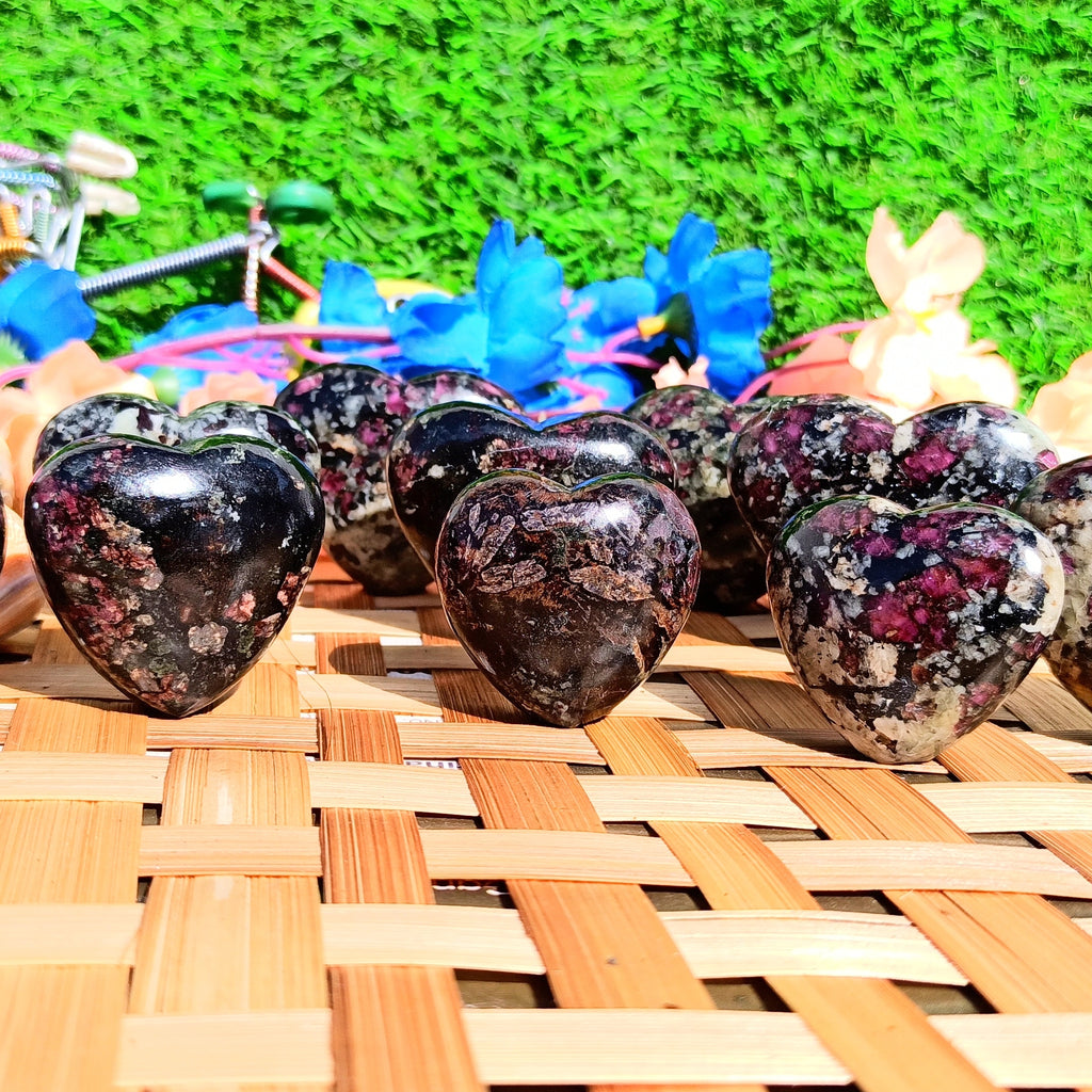 Heart-shaped stones with floral patterns on a woven surface with a grassy background